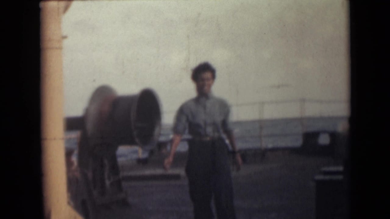 Woman on a ship deck near large marine equipment and railing in 1946 India-related 8mm footage.