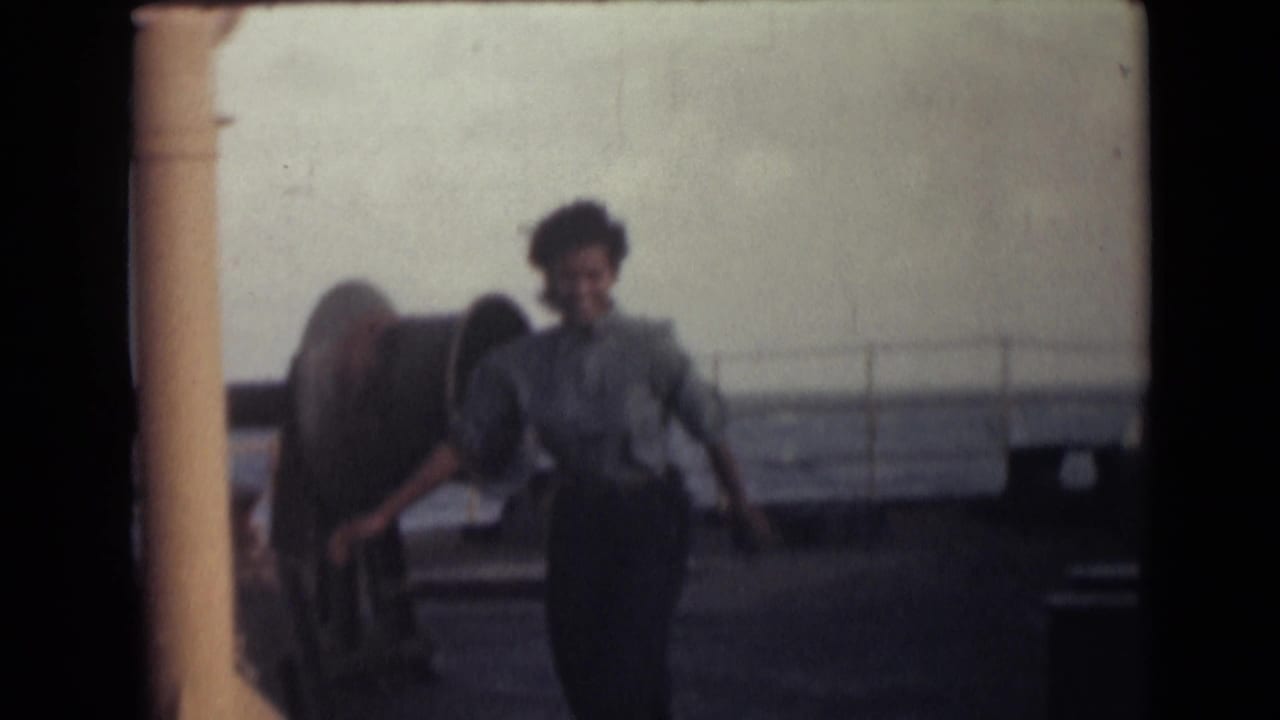 Woman walking or running on a ship deck near railings and a yellow column.