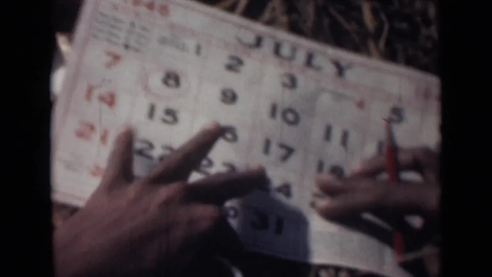 Hands hold a July 1946 calendar page while a pencil points near the numbered dates.