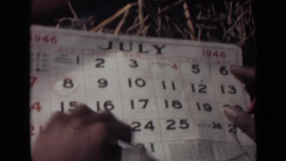 In 1946 India home-movie footage, hands point across a July calendar page with one date circled in red.