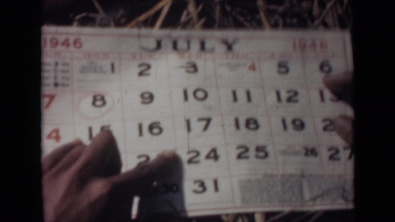 Hands hold a July 1946 calendar page while a finger points near the dates.