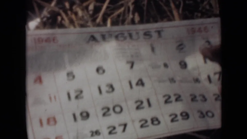 1946 India home-movie frame showing an August calendar page with red and black dates, seen softly through 8mm film grain.