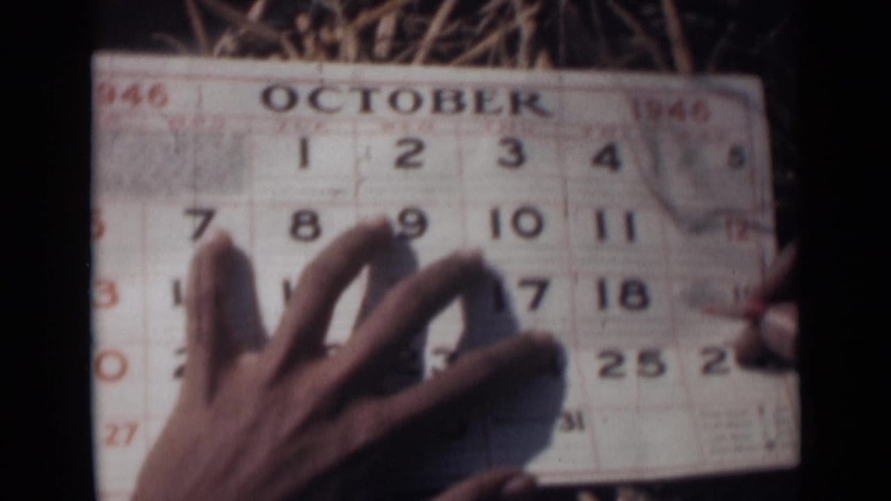 Hand holding an October 1946 calendar page on straw.