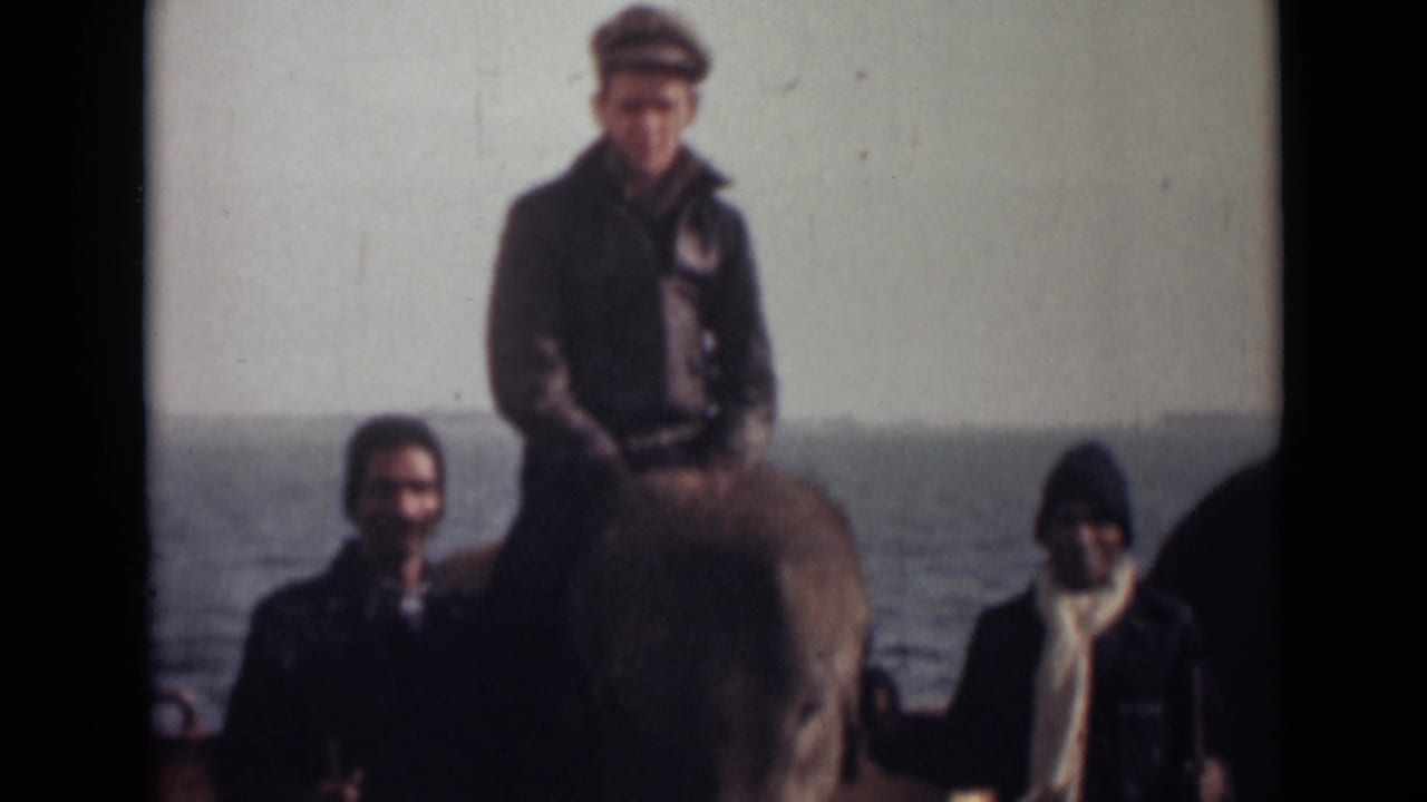 In the final frame, the capped man sits atop the elephant while two men stand nearby on the deck against a water background.