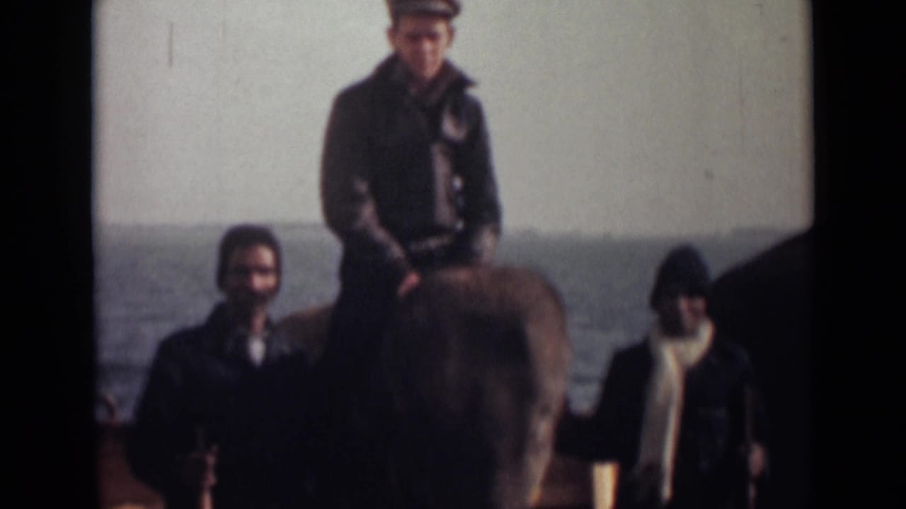 1946 India 8mm frame showing a man in a cap on an elephant beside two men, with open water in the background.