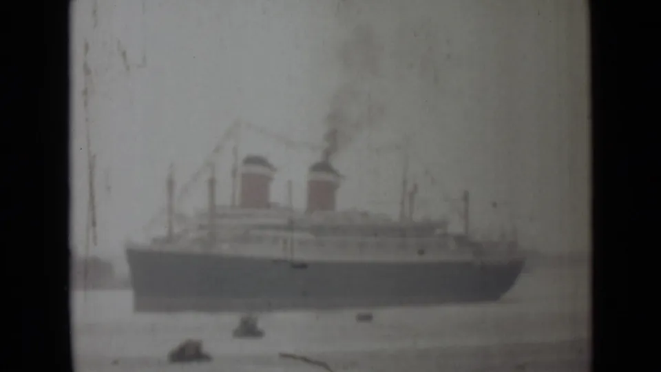 Soft 1946 India 8mm frame of a large steamship seen across water with smoke and small boats nearby.