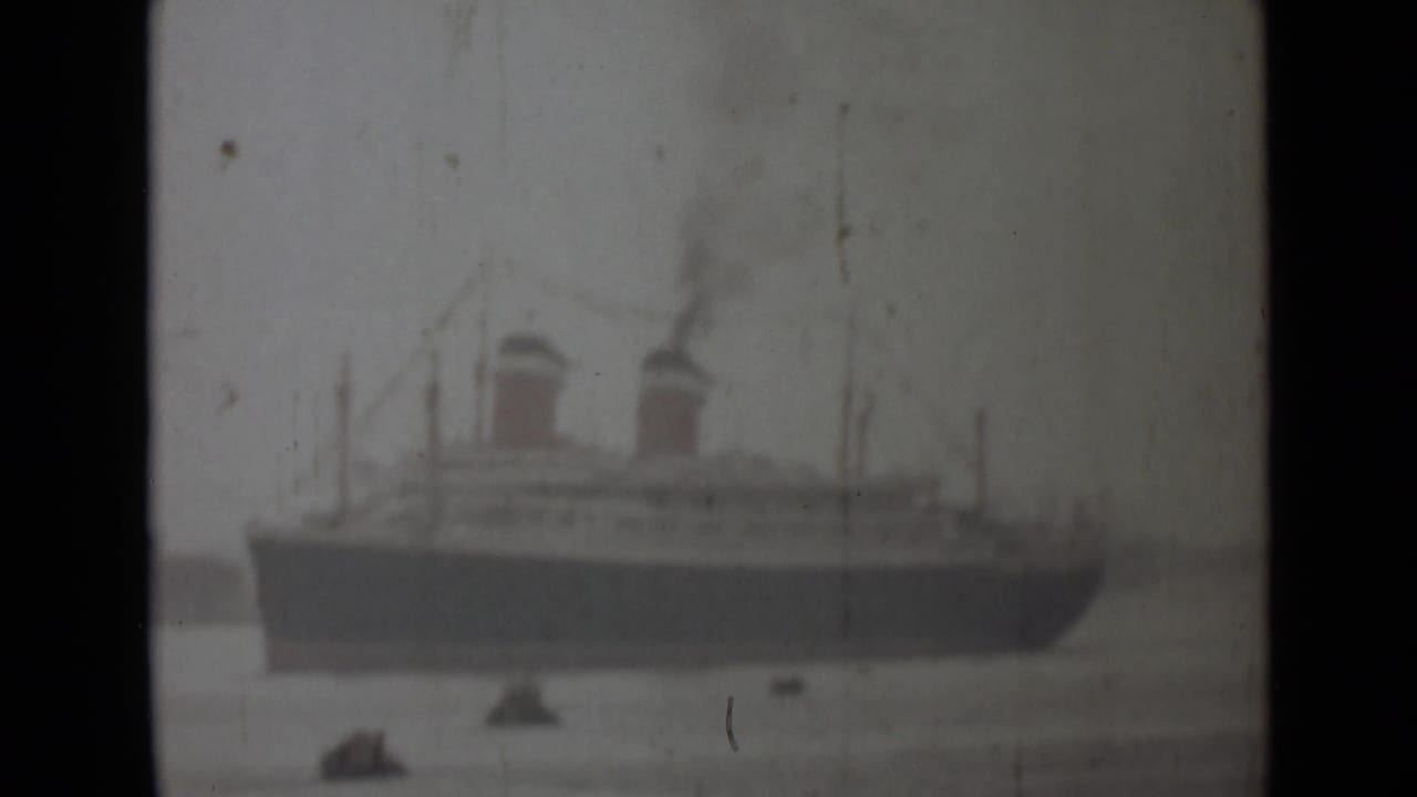 1946 India 8mm frame showing a large twin-funnel steamship across the water, with smoke and small craft nearby.