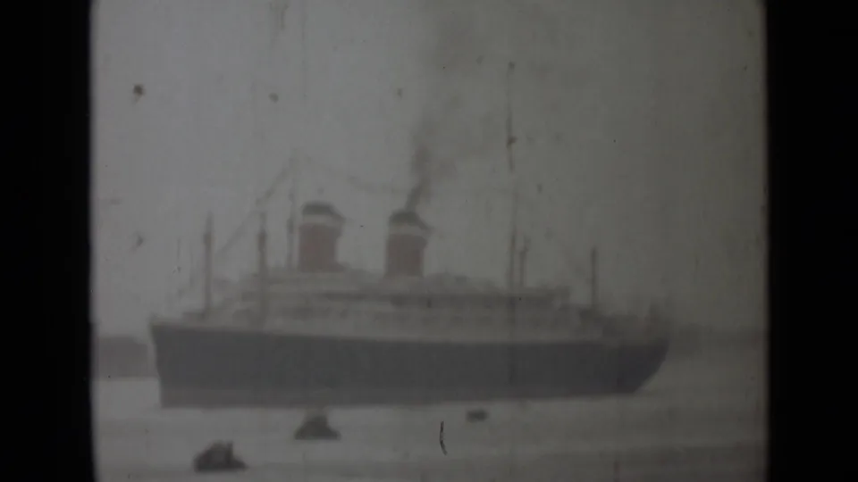 1946 India 8mm frame showing a large twin-funnel steamship across the water, with smoke and small craft nearby.
