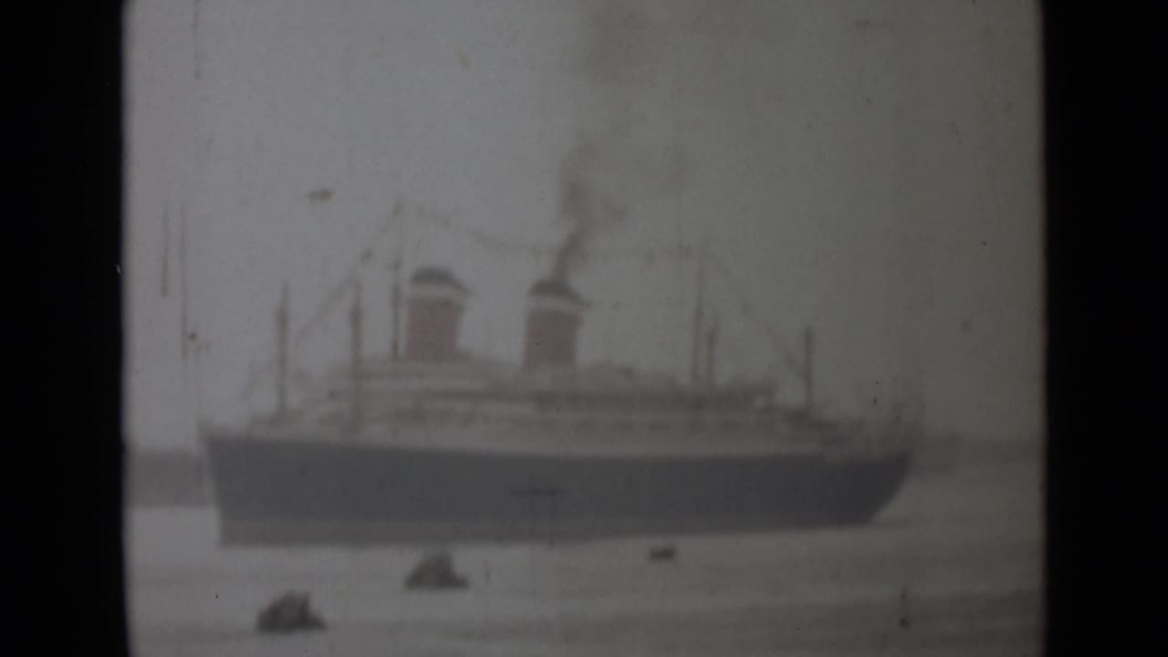 Faded 1946 India 8mm frame showing a large passenger ship in profile, with two smoking funnels and small boats on calm water.