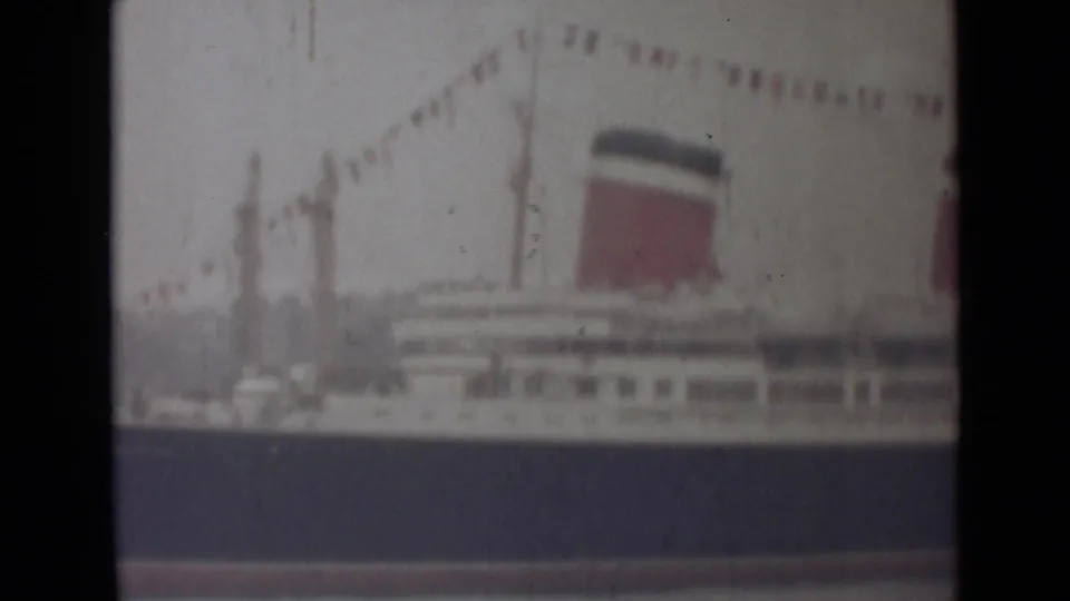 Soft 8mm view of a passenger liner in India, showing deck rows, a red-and-dark funnel and signal flags overhead.