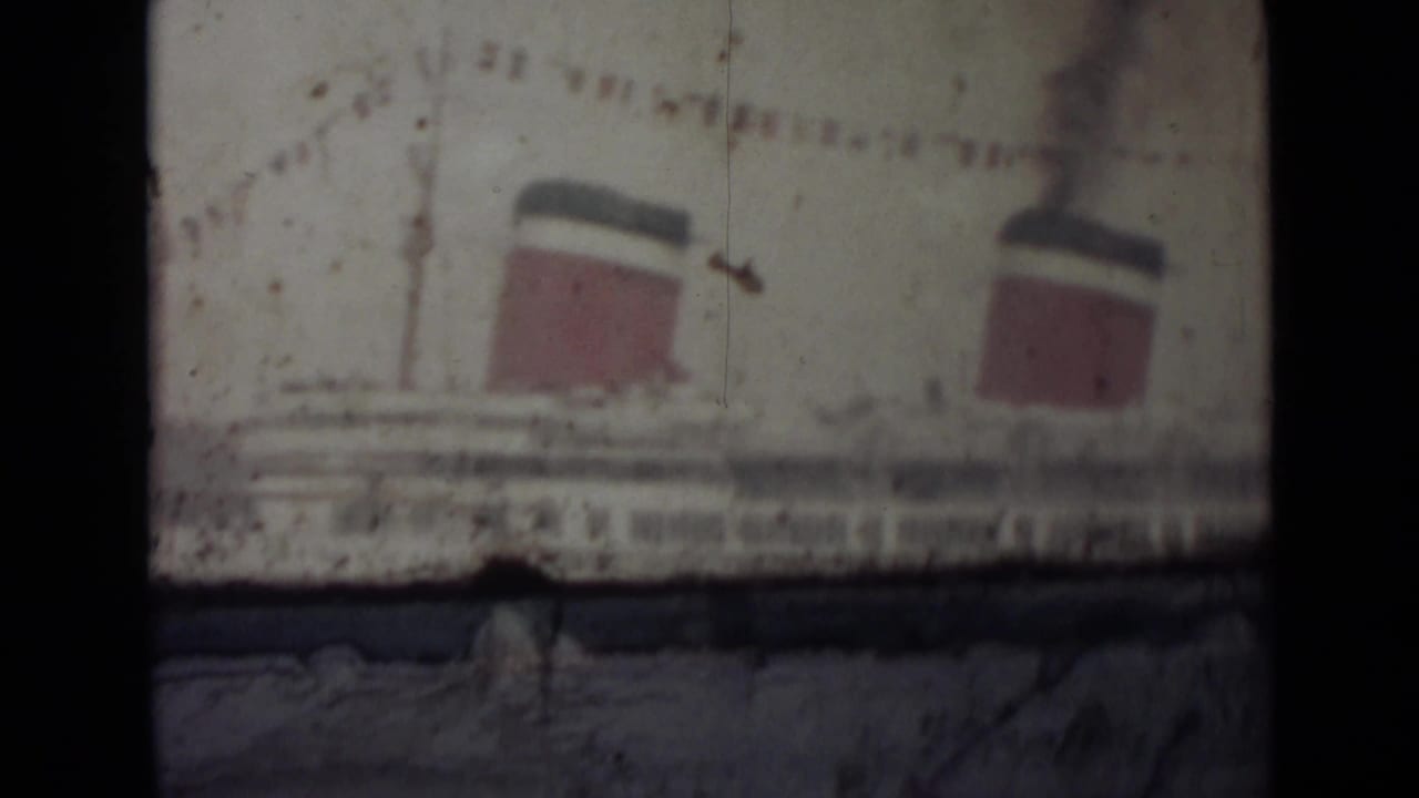 Similar view of the ocean liner, partly obscured by dark film borders and scratches.