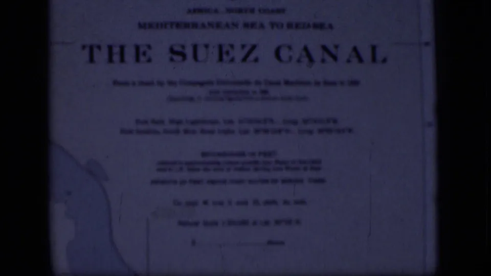 1946 8mm frame from Egypt showing a soft, blue-tinted sign headed The Suez Canal with route text and a partial map outline.
