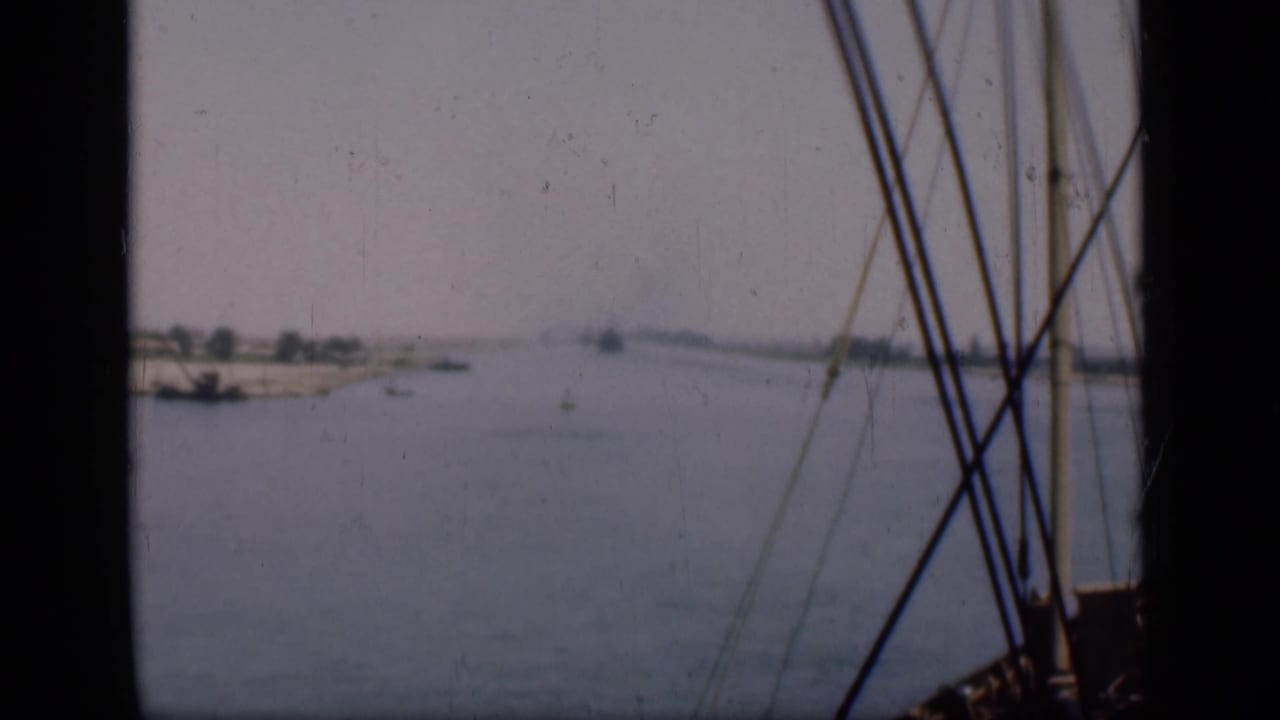 Suez Canal waterway stretching into a hazy distance, filmed past rigging from a low boat perspective.