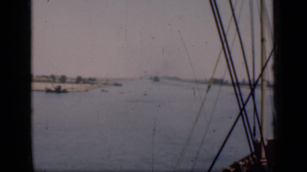 1946 Suez Canal view through boat rigging, with muted water, low banks, and small distant craft.
