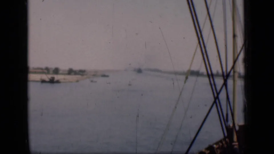 1946 Suez Canal view through boat rigging, with muted water, low banks, and small distant craft.