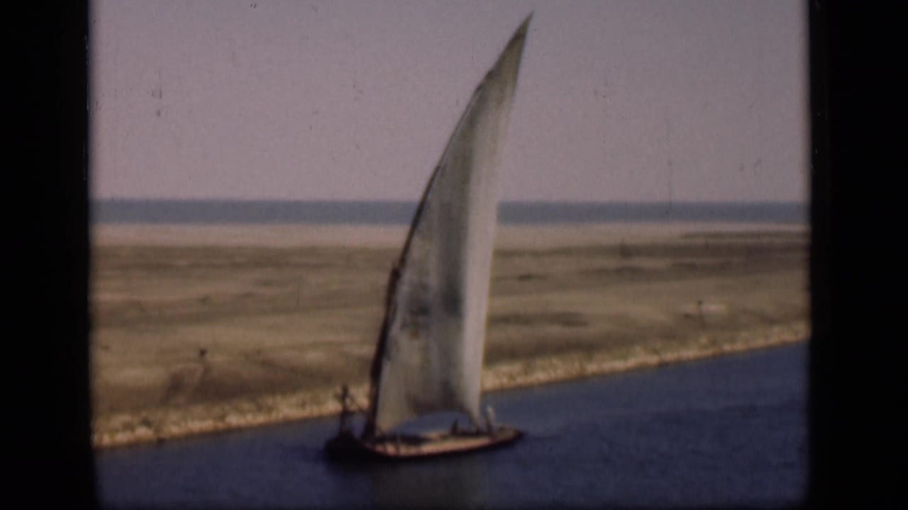 1946 Suez Canal frame with a small wooden felucca and tall lateen sail passing along the waterway.