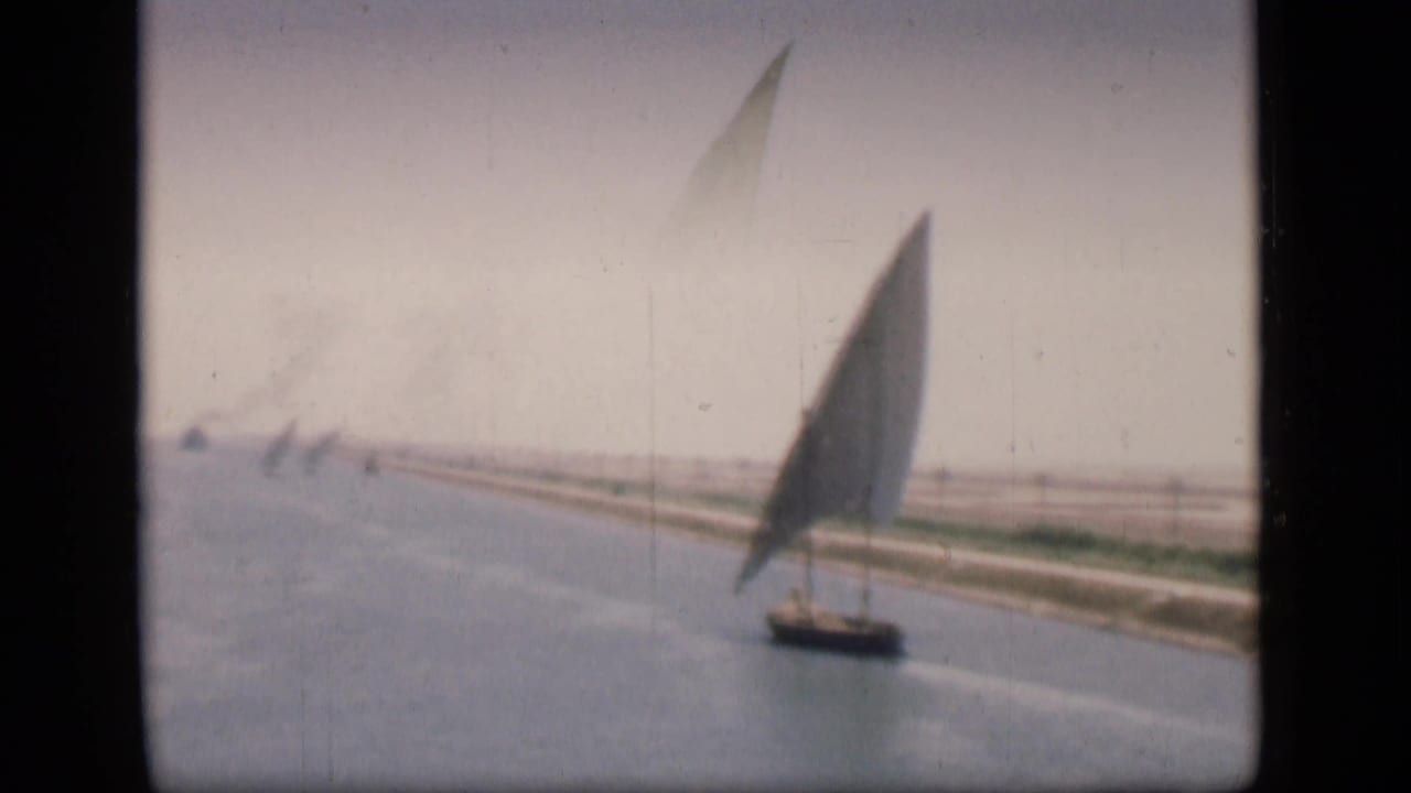 Soft 1946 Suez Canal frame showing a felucca from farther away, with faint sailboats along the canal line.