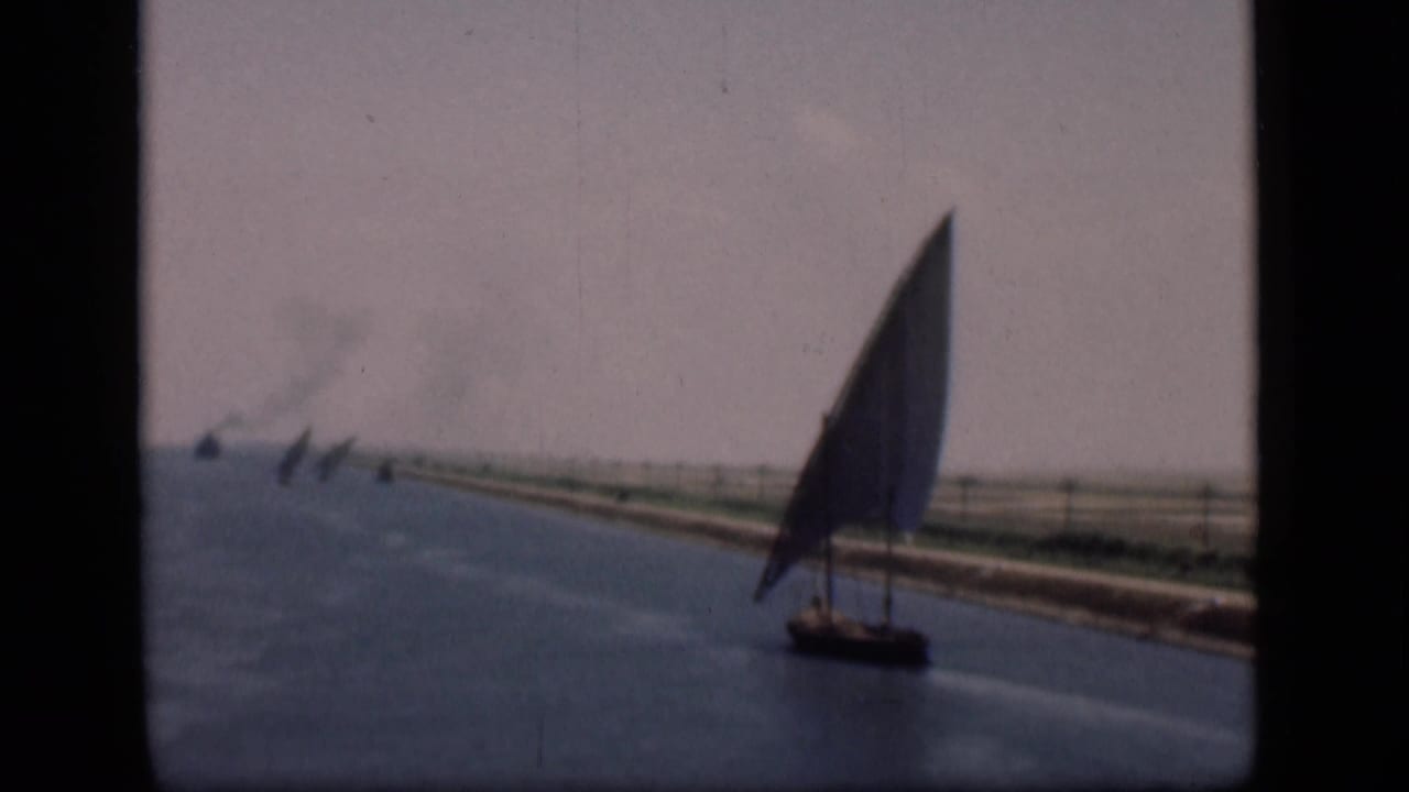 1946 Suez Canal home-movie frame showing the felucca in darker exposure as it travels beside the canal bank.