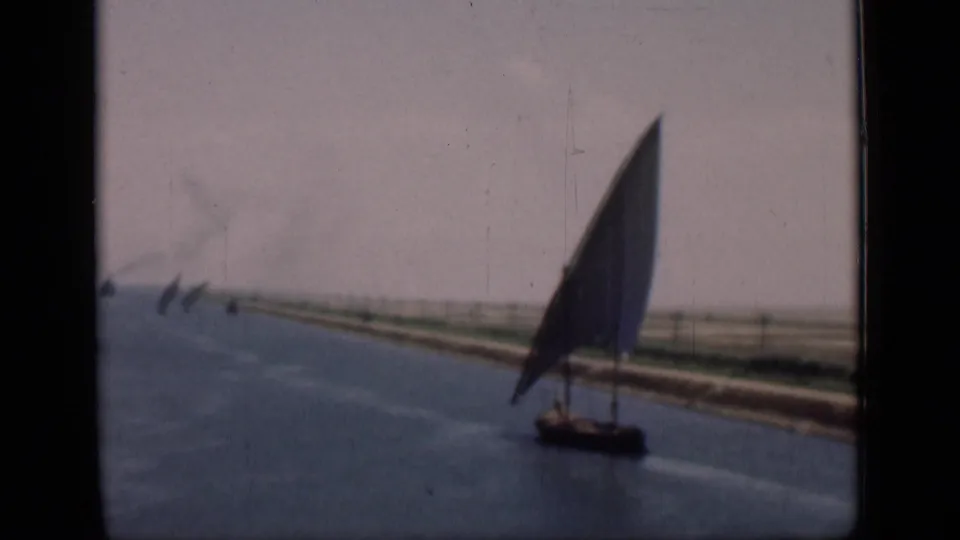 A felucca with a tall triangular sail moves along the Suez Canal in 1946-era 8mm home-movie footage.