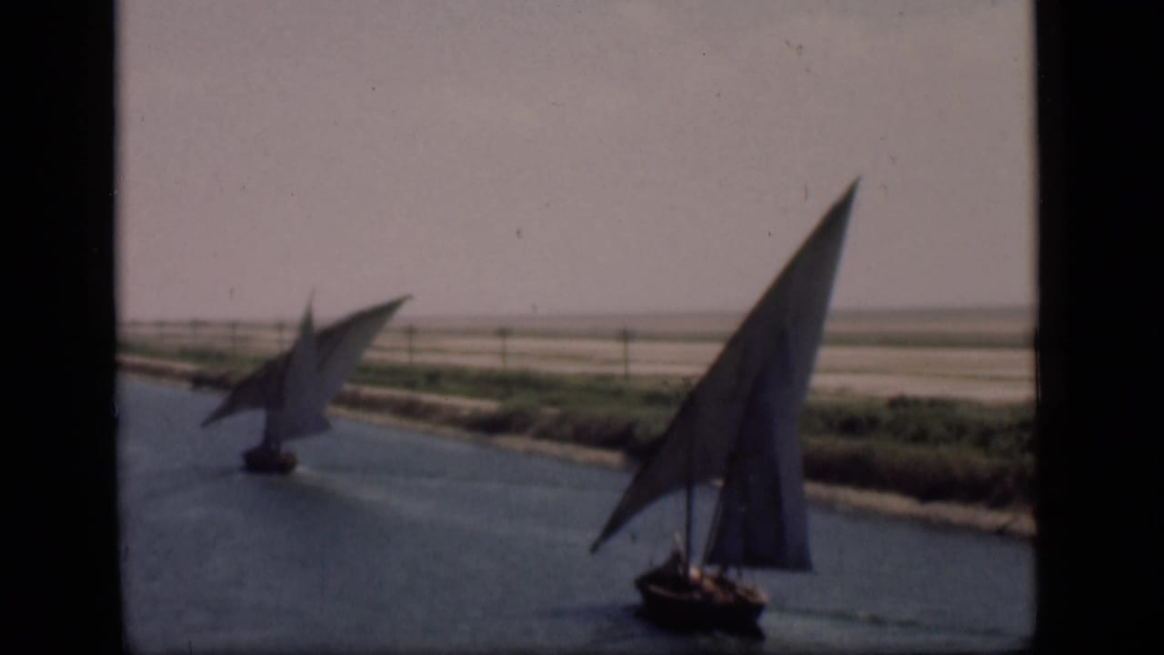 Final 1946 Suez Canal frame showing two traditional sailboats moving along calm water beside a sparse shoreline.