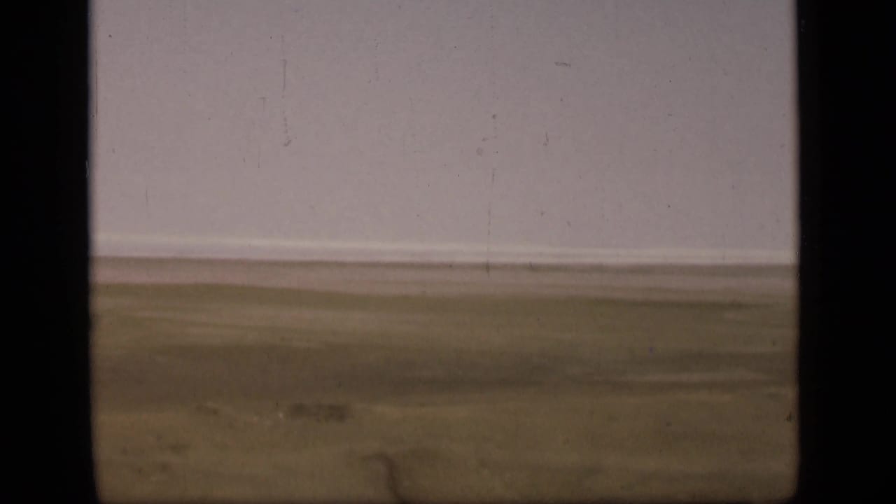 1946 Suez Canal area footage showing a distant flat plain beneath a pale sky, framed by dark 8mm contact-sheet borders.