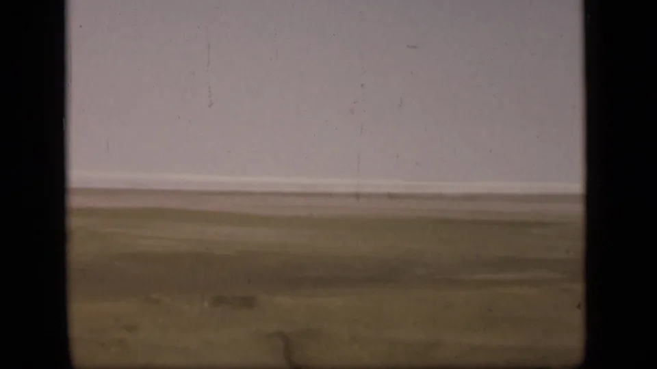 1946 Suez Canal area footage showing a distant flat plain beneath a pale sky, framed by dark 8mm contact-sheet borders.