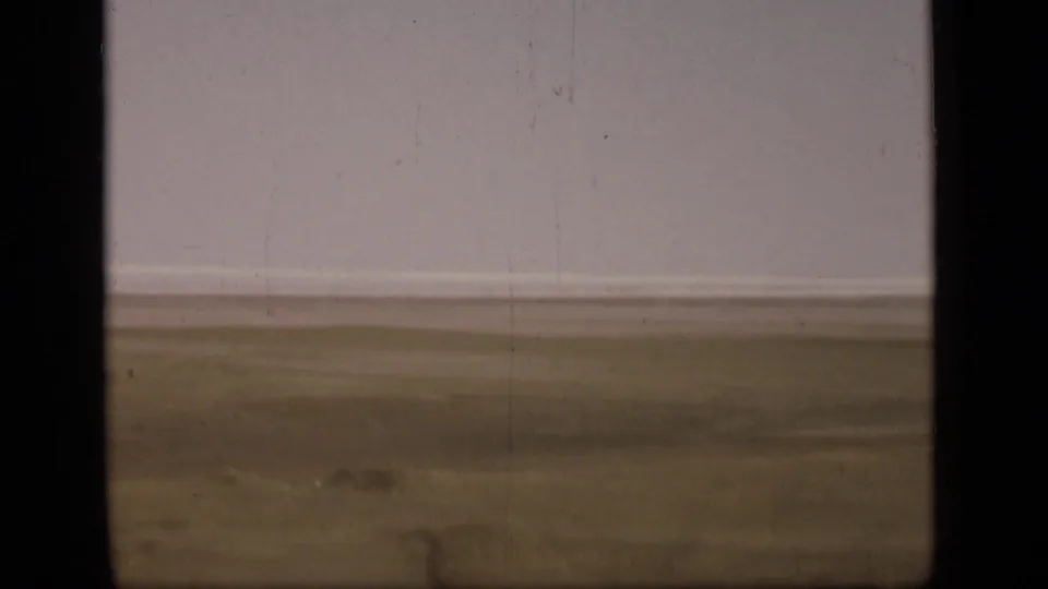 A soft 8mm view of flat terrain near the Suez Canal in Egypt, with muted ground tones and a broad pale sky.