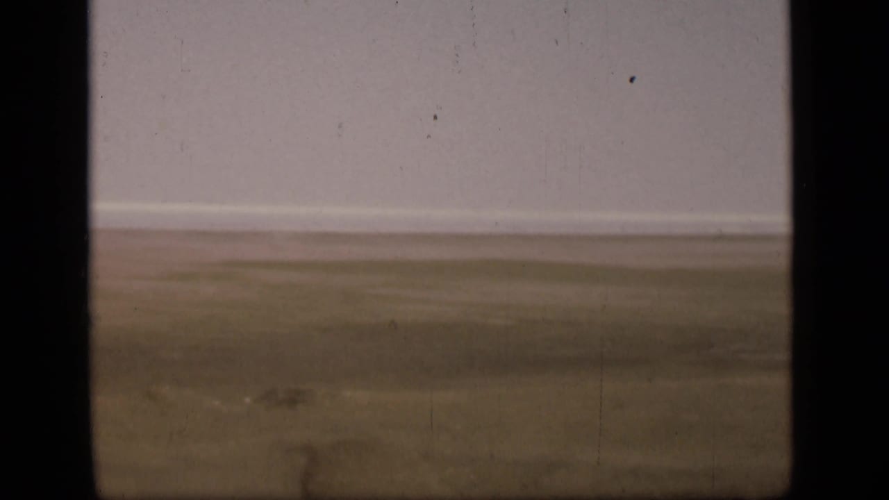 The final frame shows flat open ground near the Suez Canal, a pale sky, and aged 8mm film texture.