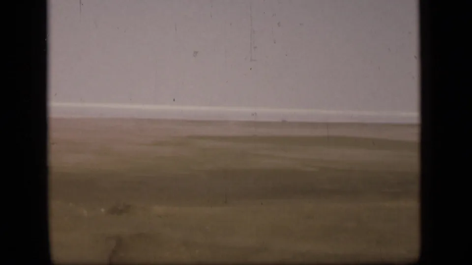 Soft 8mm frame of the Suez Canal region landscape, showing empty desert ground, a distant horizon, and aged film texture.