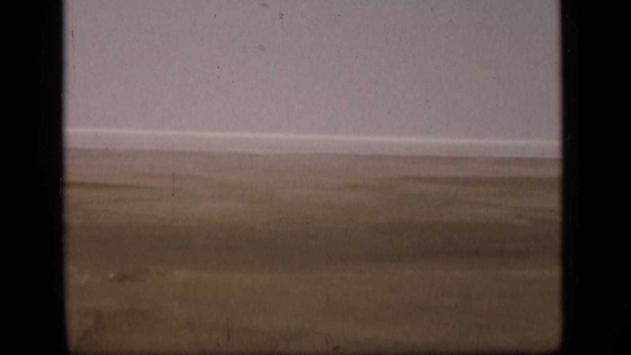 Soft 8mm view of empty desert terrain in the Suez Canal region, with a distant horizon and visible grain, dust, and scratches.