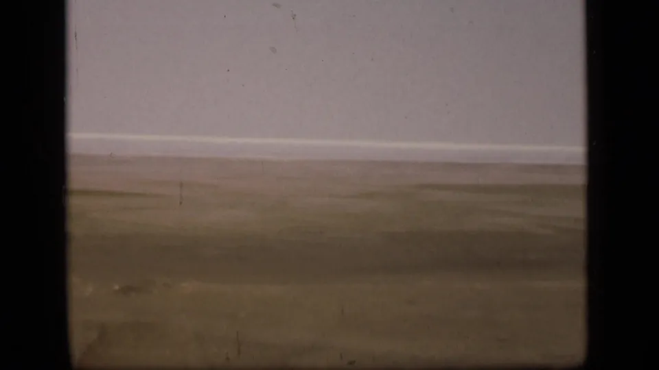 Soft 8mm view of empty desert terrain in the Suez Canal region, with a distant horizon and visible grain, dust, and scratches.