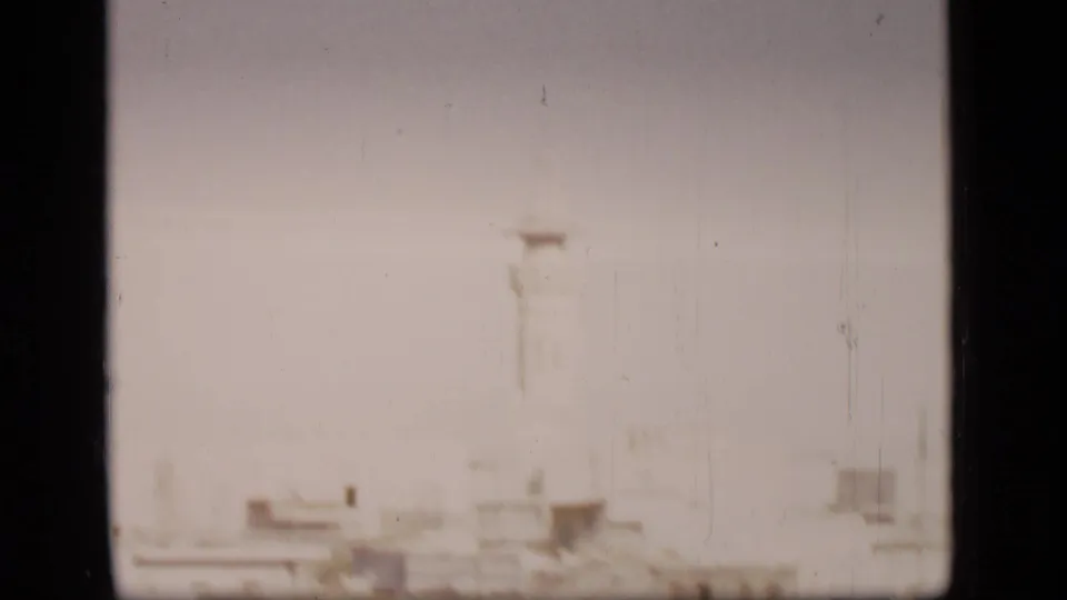 Soft, overexposed 1946 8mm view in the Suez Canal region, showing a faint sandy or urban edge through heavy haze.