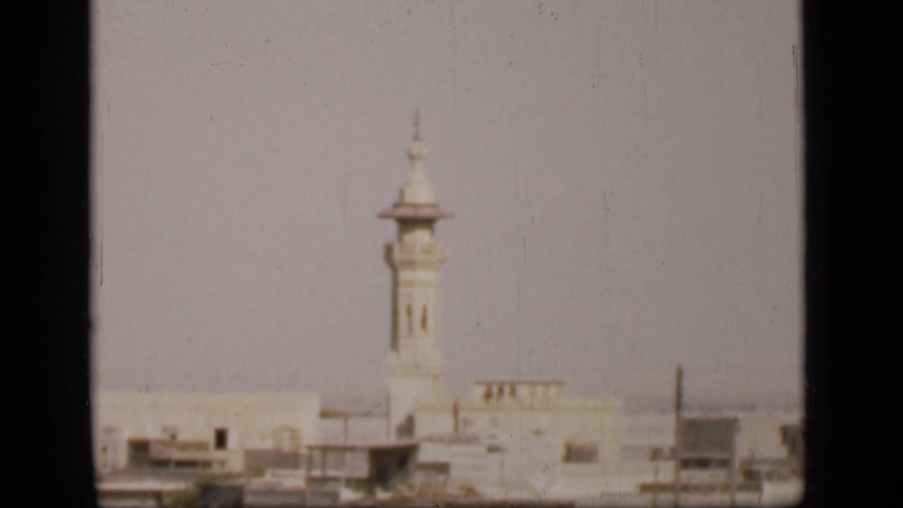 1946 Egypt home-movie frame showing a white minaret, pale urban buildings, and a muted skyline in the Suez Canal region.