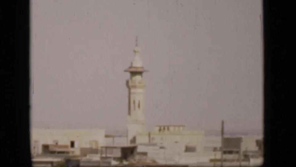 1946 Egypt home-movie frame showing a white minaret, pale urban buildings, and a muted skyline in the Suez Canal region.