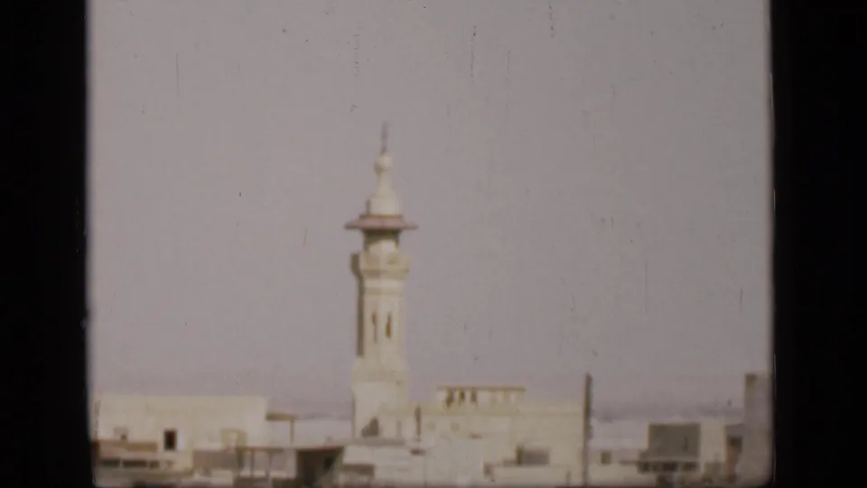 1946 8mm view of a white minaret and low buildings in the Suez Canal region, seen through soft focus and visible film wear.