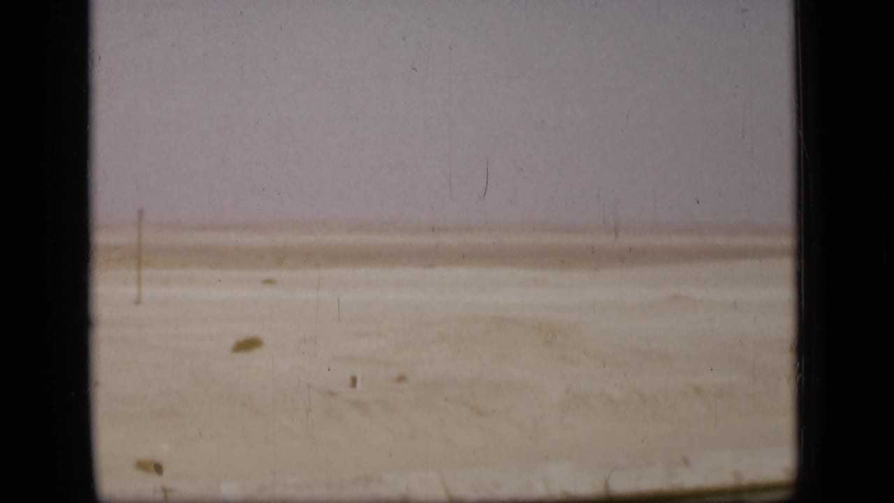 Final 1946 Suez Canal region frame showing flat sandy terrain, faint poles, and the aged borders of the 8mm film scan.