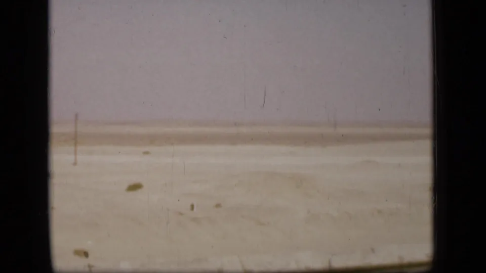 Final 1946 Suez Canal region frame showing flat sandy terrain, faint poles, and the aged borders of the 8mm film scan.