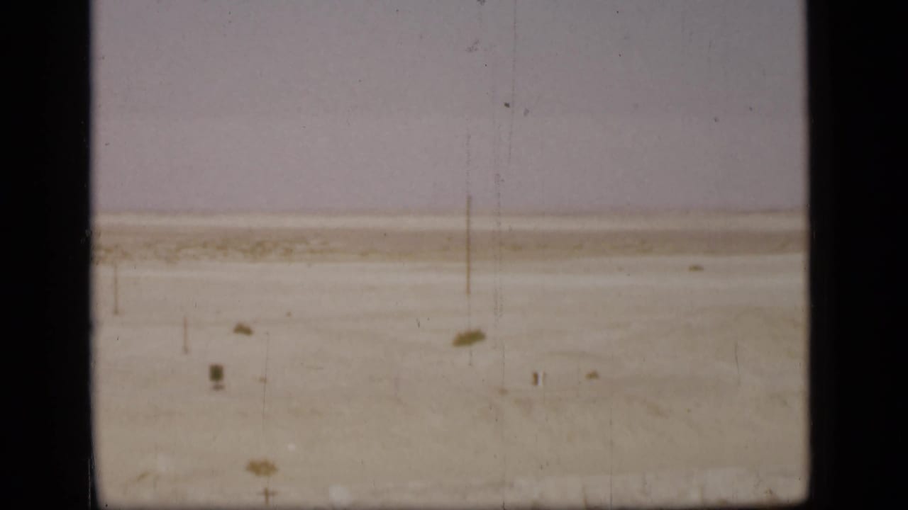 1946 Suez Canal area landscape with a barren pale sand plain, sparse scrub, and a single pole or marker in the distance.