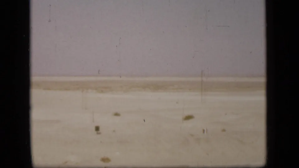 A muted 1946 8mm view of the Suez Canal area desert, showing flat sand, scattered scrub, and aged film wear.