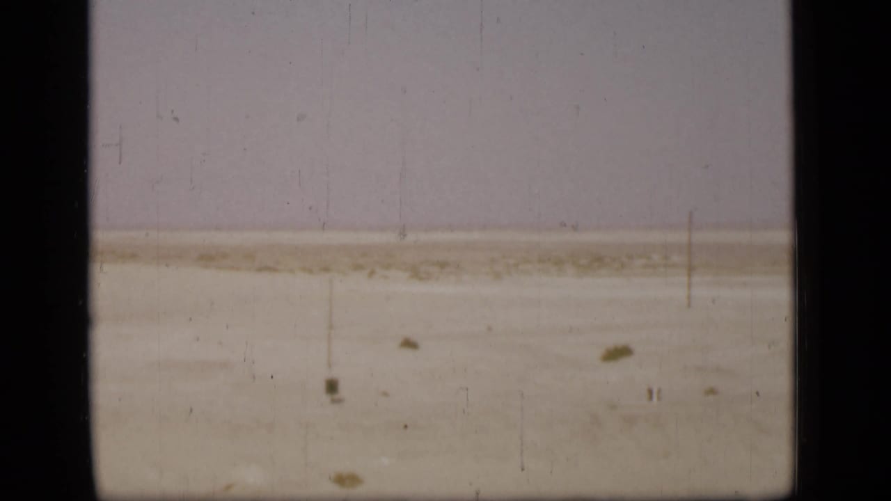 1940s Suez Canal view with a pale shoreline and flat water seen through dark film or window borders.