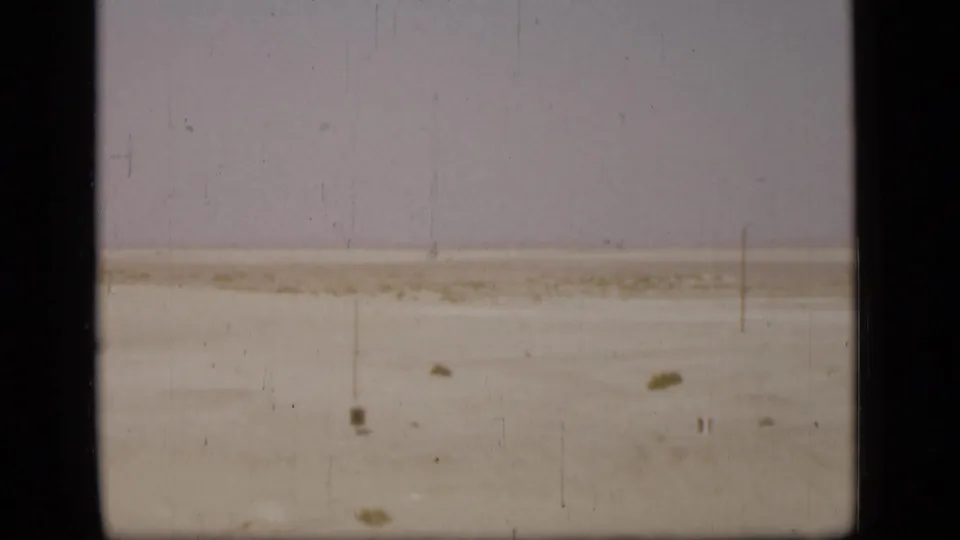 1940s Suez Canal view with a pale shoreline and flat water seen through dark film or window borders.