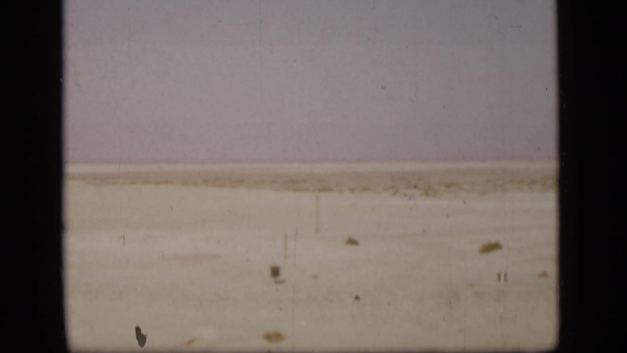 Suez Canal shoreline and waterway appear in faded 8mm color, with a dark border cutting through the frame.