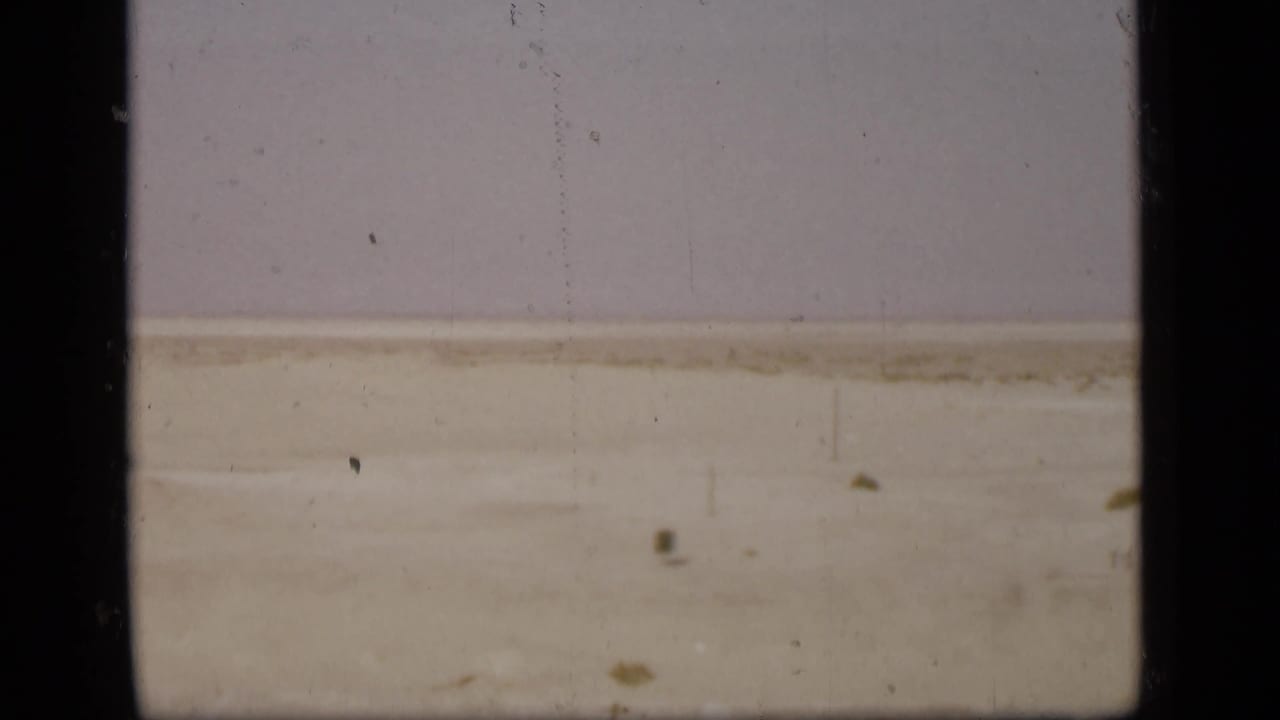 A pale Suez Canal-side landscape appears in soft, faded 8mm color with dust and vertical film marks.