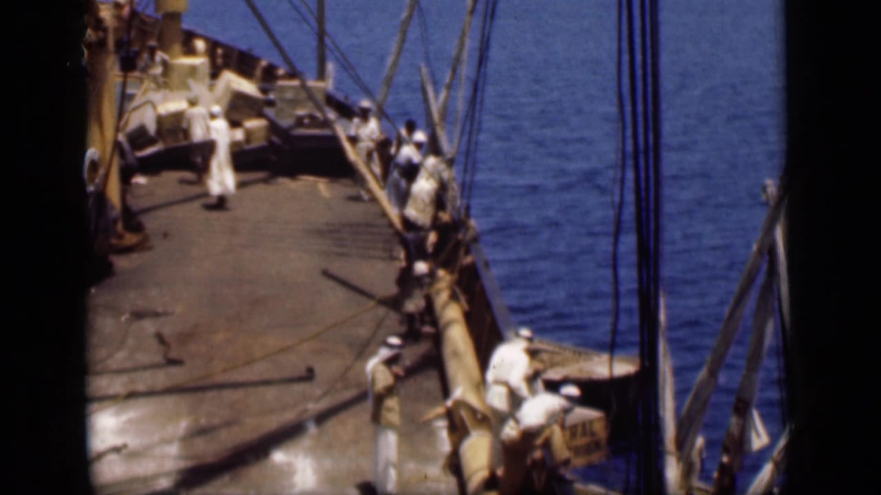 Mid-1940s Suez Canal home-movie frame of men on a sailing vessel deck, with rigging, deck gear, and blue water in view.