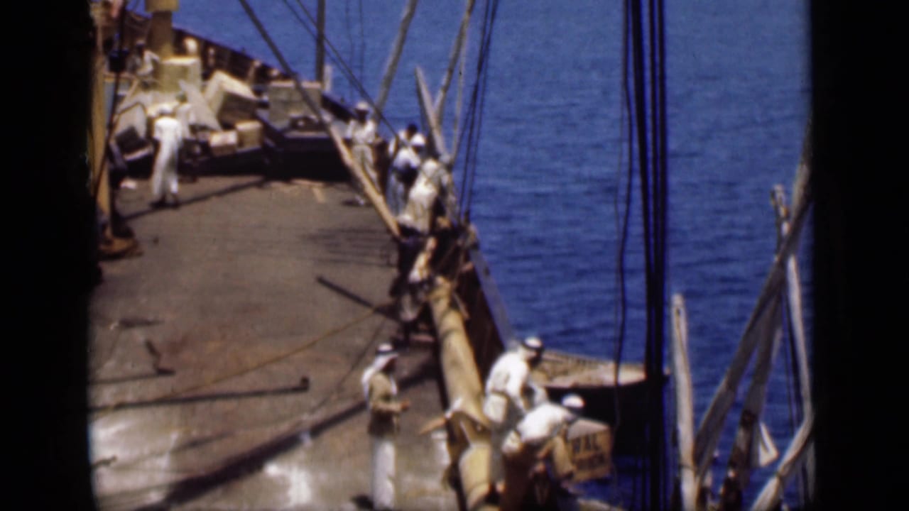 1946 Suez Canal frame looking down on crew members handling or standing near ropes on a wooden sailing vessel deck.