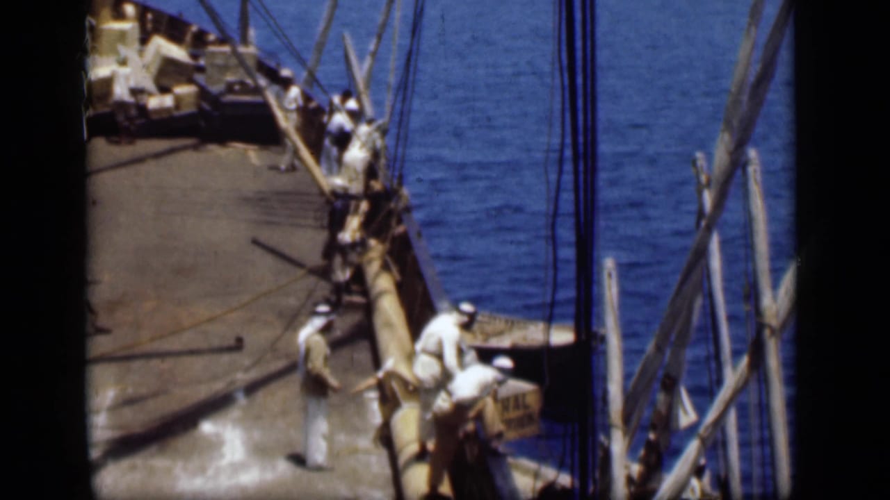 On the Suez Canal in 1946, men in white robes and Arab headdresses stand near a cargo vessel's gunwale and rigging.