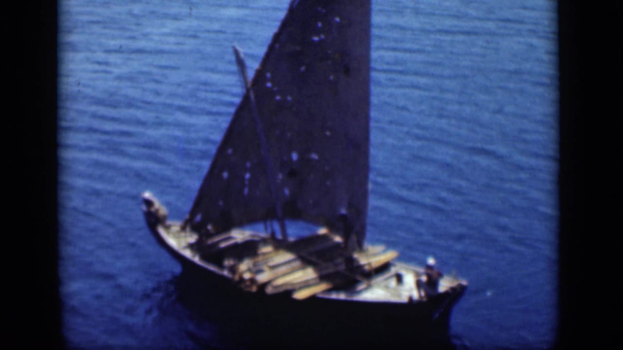 High-angle 1946 Suez Canal view of a wooden sailboat with a dark sail and small crew figures on deck.