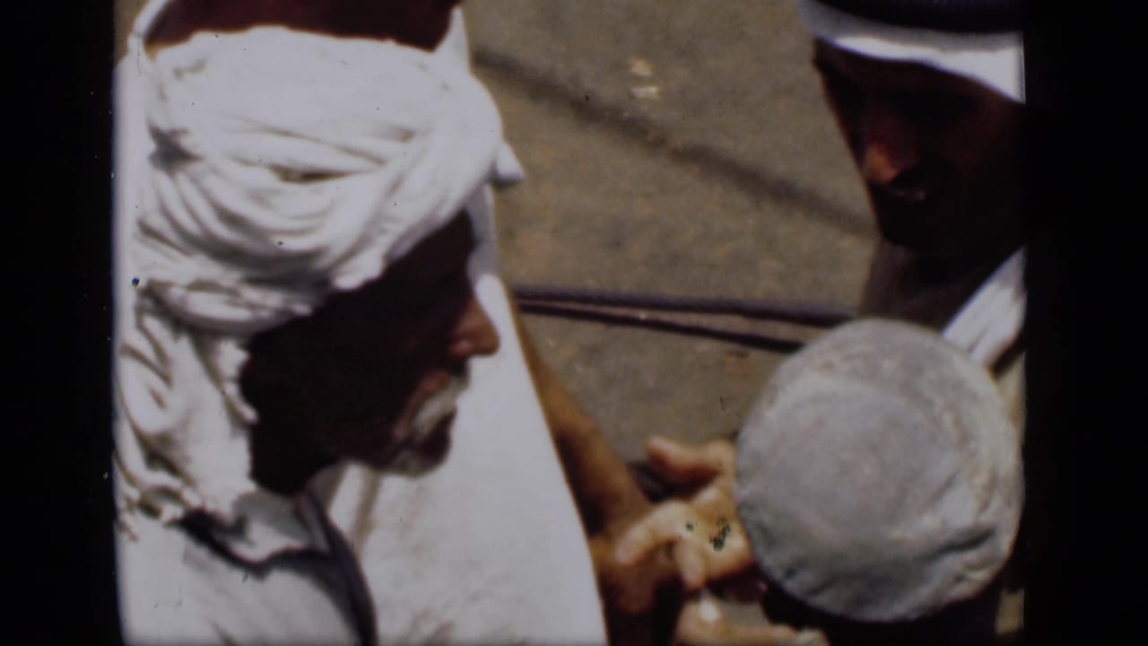Close 1946 Suez Canal home-movie view of men in white head coverings handling or counting a small item in harsh sunlight.