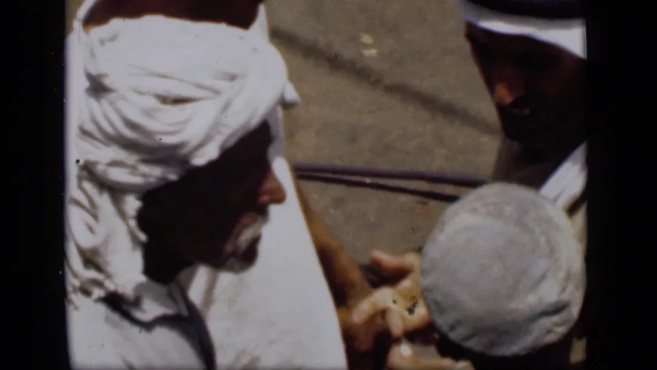 Close 1946 Suez Canal home-movie view of men in white head coverings handling or counting a small item in harsh sunlight.