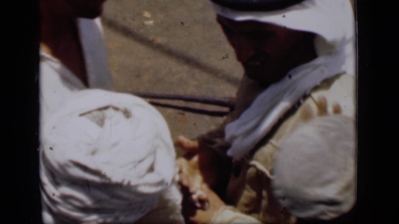 Close view of men in white head coverings and robes on a sunlit boat deck.